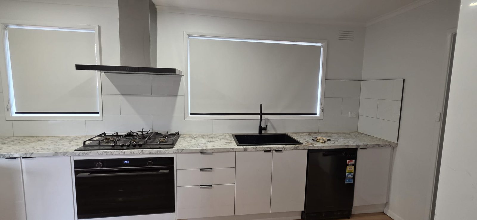 Renovated modern white kitchen with stone benchtop and black tapware in Thomastown, Melbourne
